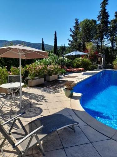 une piscine avec deux chaises et un parasol dans l'établissement Mazet 2 pers dans havre de paix cévennol, à Laroque