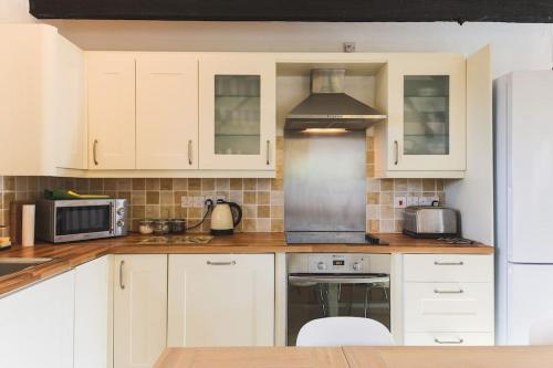 a kitchen with white cabinets and a stove top oven at Mill House @ Goonwinnow Farm in Newquay