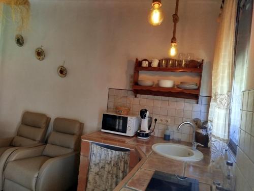 cocina con encimera, microondas y sofá en CASA RURAL "LA CASITA" para 2 personas, en Ronda