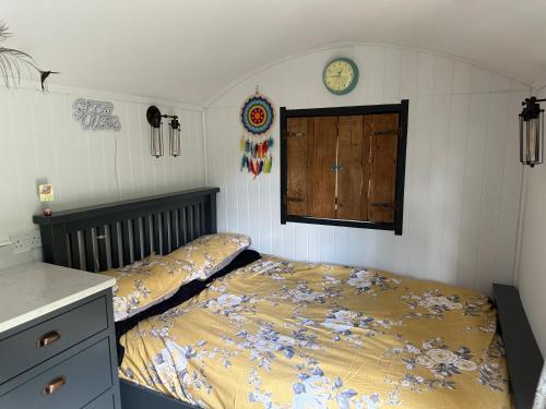 a bedroom with two beds and a clock on the wall at A Snuggles hut in Faversham