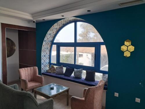 a living room with an arch window and a blue wall at Dar Salem in Djerba