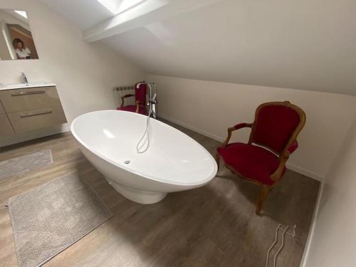 La salle de bains est pourvue d'une baignoire et d'une chaise rouge. dans l'établissement Villa Le Lébérou, à Sarlat-la-Canéda