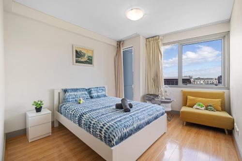 Un dormitorio con una cama y una silla y una ventana. en Central CBD 3BR Apt & DarlingHabour&Chinatown-2 mins walk, en Sídney