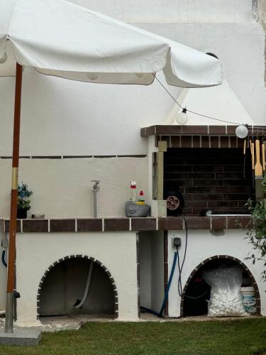 a white umbrella standing next to a pizza oven at Momo's House in Nikiti