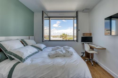 a bedroom with a large white bed with a window at Maison des Marais 5 Etoiles La Chaume Piscine in Les Sables-dʼOlonne
