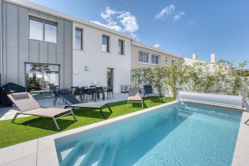 une arrière-cour avec une piscine, des chaises et une maison dans l'établissement Maison des Marais 5 Etoiles La Chaume Piscine, à Les Sables-dʼOlonne