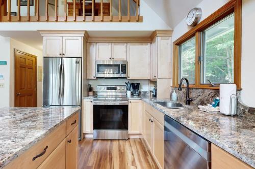 a kitchen with white cabinets and stainless steel appliances at Meadow Cove in Boothbay