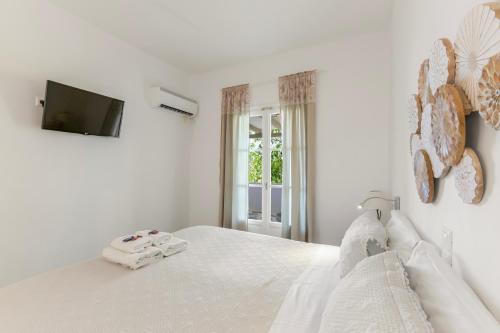a white bedroom with a bed and a television at Margarita Studios Ambelas in Ambelas