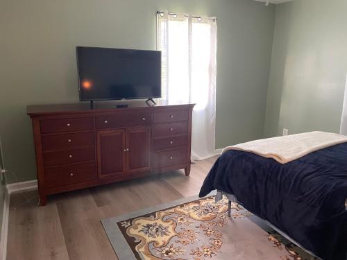 a bedroom with a dresser with a flat screen tv on it at Gallimore TLC bungalow in Elmira