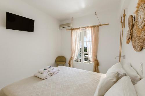 a bedroom with a white bed and a window at Margarita Studios Ambelas in Ambelas
