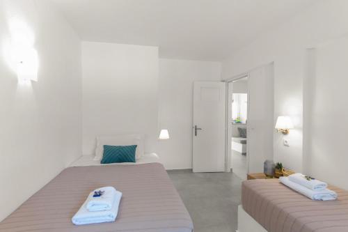 two beds in a white room with towels on them at Margarita Studios Ambelas in Ambelas