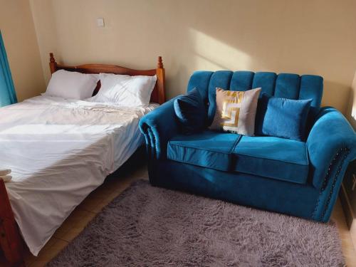 a bedroom with a blue couch next to a bed at Studio Apartment near the Airport in Nairobi