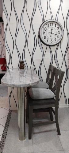 a table and a chair and a clock on a wall at Jack Kandi Grosvenor Square in Angeles
