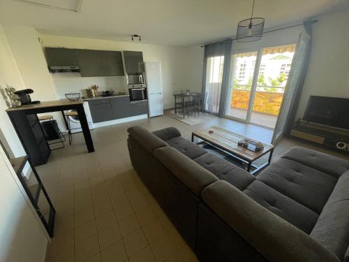 Il comprend un grand salon avec un canapé et une cuisine. dans l'établissement Lumineux T2 - Ajaccio proche mer, à Ajaccio