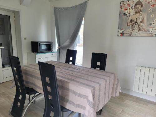 une salle à manger avec une table, des chaises et un tableau dans l'établissement Gîte à Romagné, à Romagné