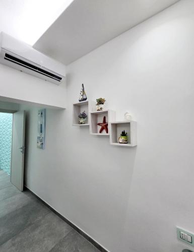 a white room with white shelves on the wall at Aquamarina Rooms in Porto Cesareo