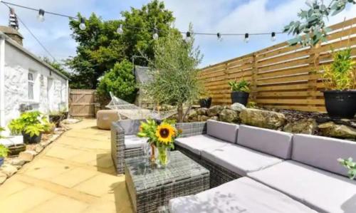 ein Garten mit einer Bank und einer Vase mit einer Sonnenblume in der Unterkunft Detached cottage near to Abersoch in Abersoch