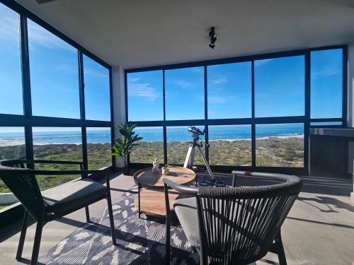 a room with a table and two chairs and windows at Starfish Beach Villa in St. Helena Bay