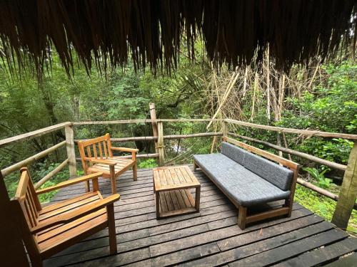 a deck with two benches and a couch and a table at Las Cabañas del Rio in Minca