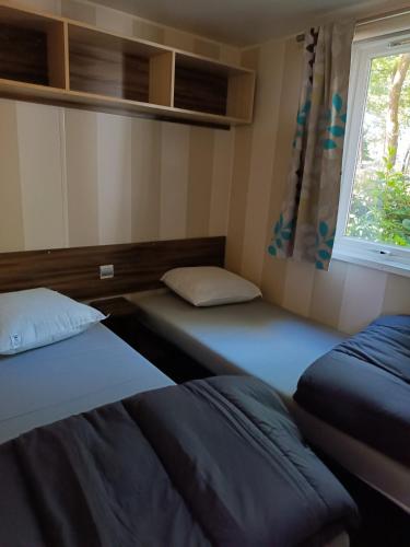 deux lits dans une chambre avec une fenêtre dans l'établissement Mobil-home en pleine Nature, à La Boissière-de-Montaigu