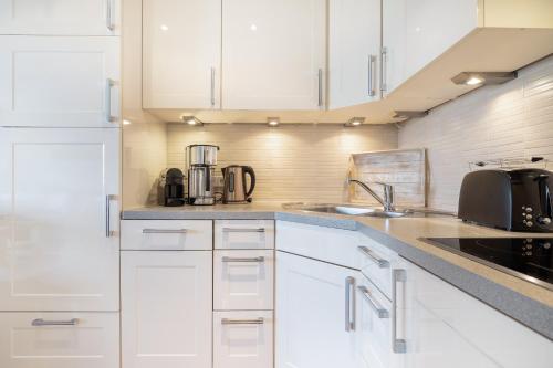a white kitchen with white cabinets and a sink at Adis Meerblick Landhaus Arnika HT 2 in Wenningstedt