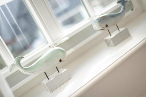 two bird figurines sitting on a window sill at Adis Meerblick Landhaus Arnika HT 2 in Wenningstedt