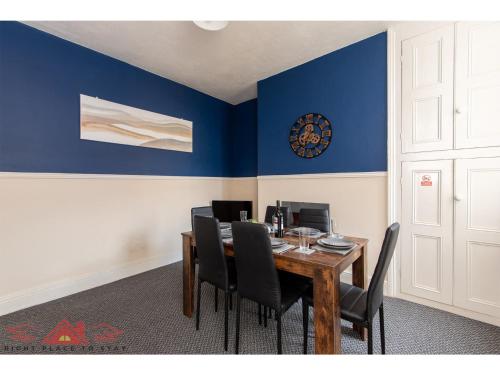 a dining room with blue walls and a table with black chairs at Darlington Modern 2 Bed Apartment Great for Contractors in Darlington