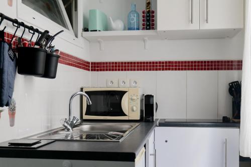 une cuisine avec un évier et un micro-ondes dans l'établissement Studio tout équipé emplacement parfait sur la baie des Sables d'Olonne, à Les Sables-dʼOlonne