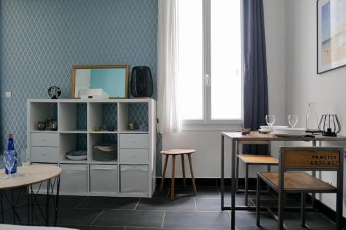 une salle à manger avec une armoire blanche et une table dans l'établissement Studio tout équipé emplacement parfait sur la baie des Sables d'Olonne, à Les Sables-dʼOlonne