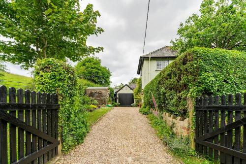 a driveway leading to a house with a fence at Cedra Cottage - Vintage Country Hideaway in Axminster