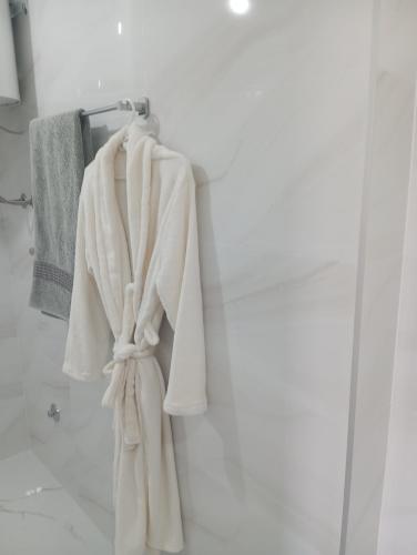 a white robe hanging on a towel rack in a bathroom at Apartmani Mušinbegović in Visoko