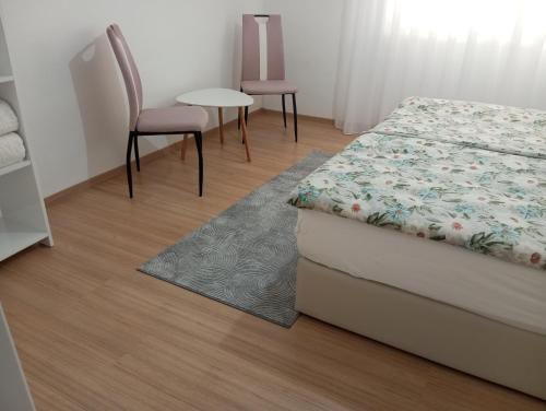 a bedroom with a bed and two chairs and a table at Apartmani Mušinbegović in Visoko