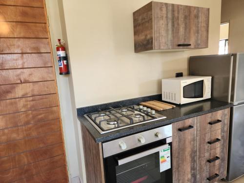 a kitchen with a stove top oven next to a microwave at Lloyds - 6 in Ermelo