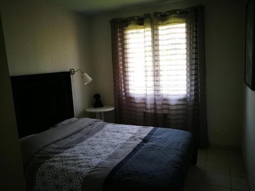 une chambre avec un lit et une fenêtre avec des rideaux dans l'établissement Appartement Mandelieu la Napoule, à Mandelieu-la-Napoule