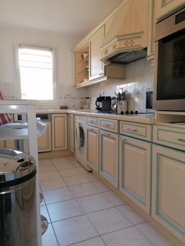 une cuisine avec des armoires en bois et une laveuse et une sécheuse dans l'établissement Appartement Mandelieu la Napoule, à Mandelieu-la-Napoule