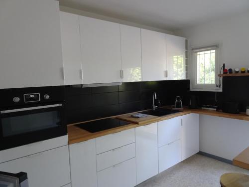 une cuisine avec des armoires blanches et un évier dans l'établissement Grande maison 3 chambres - Jardin, terrasse et parking - Bord de mer, à Torreilles