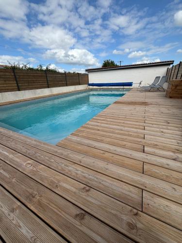 a swimming pool with a wooden deck at Cerisier in Étusson