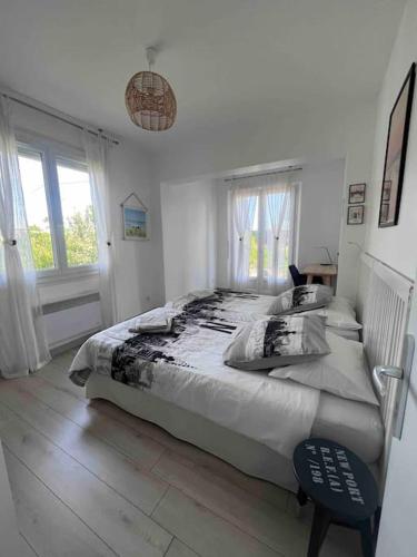 une chambre blanche avec un grand lit et une fenêtre dans l'établissement Maison à l'océan plage sud, à Lacanau