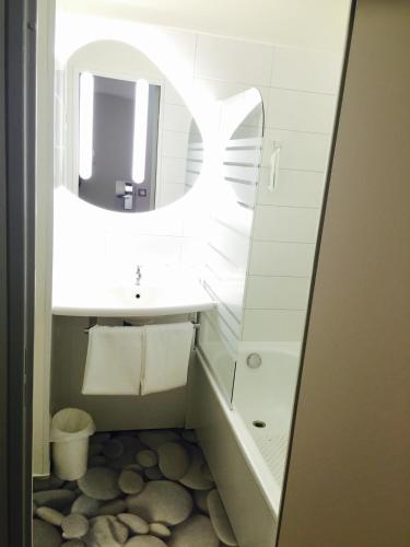 a bathroom with a white sink and a mirror at ibis budget Grigny Centre in Grigny