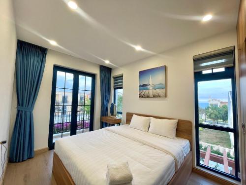 a bedroom with a bed and two large windows at Biệt thự 3 phòng ngủ Novaworld Phan Thiết in Bình Sum