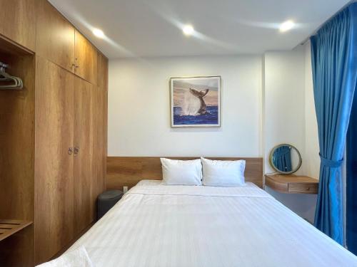 a bedroom with a large white bed with blue curtains at Biệt thự 3 phòng ngủ Novaworld Phan Thiết in Bình Sum