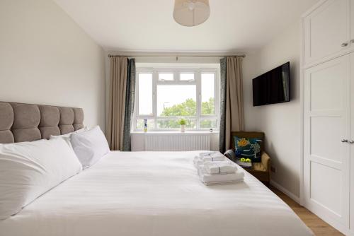a bedroom with a large white bed with a window at PenthouseStays Wimbledon - Chic 2 Bedroom King Bed Apartment with Balcony - 2 mins from Wimbledon Tennis Club and Museum - AELTC in London