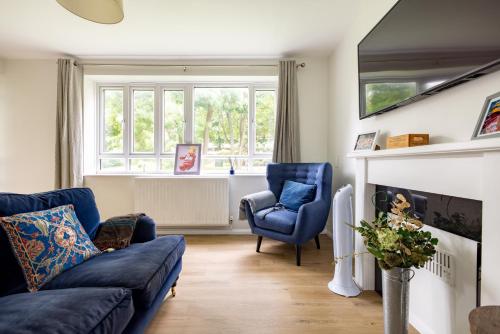 a living room with a blue couch and two chairs at PenthouseStays Wimbledon - Chic 2 Bedroom King Bed Apartment with Balcony - 2 mins from Wimbledon Tennis Club and Museum - AELTC in London