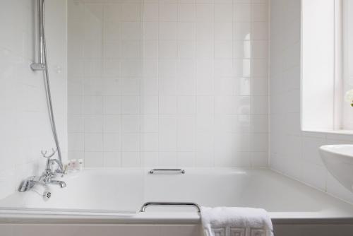 a white bathroom with a tub and a sink at PenthouseStays Wimbledon - Chic 2 Bedroom King Bed Apartment with Balcony - 2 mins from Wimbledon Tennis Club and Museum - AELTC in London