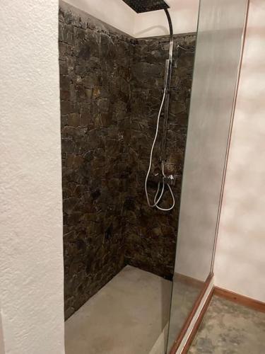 a shower in a room with a stone wall at La Spiaggia, tropical villa with private beach in Sainte Marie