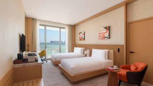a hotel room with two beds and a television at Rixos Premium Qetaifan Island North in Doha