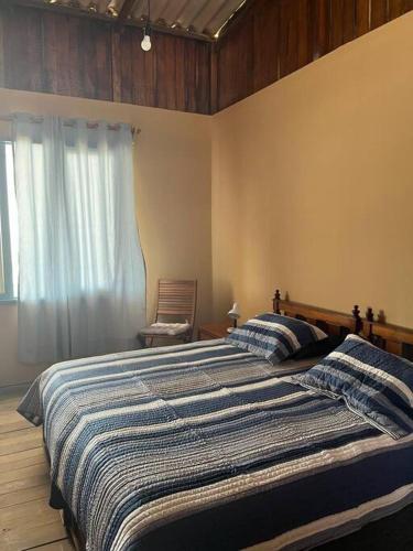 ein Schlafzimmer mit einem Bett mit einer blau-weißen gestreiften Decke in der Unterkunft Casa Esmeralda in Colán