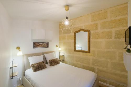 une chambre avec un lit blanc et un mur de briques dans l'établissement Les Suites d'Aliénor, Suite Cosy, à Pessac