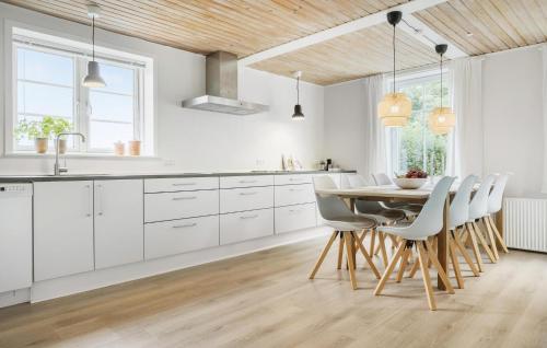 a kitchen with white cabinets and a table and chairs at 3 Bedroom Nice Home In Skærbæk in Skærbæk