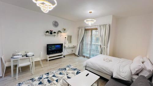 a living room with a bed and a table and a tv at Spacious Furnished studio with balcony Spain cluster International city in Dubai